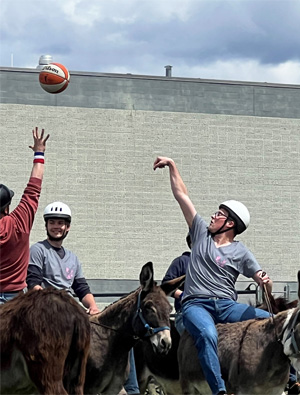 Cashmere Valley team members tossing a ball while riding Burros
